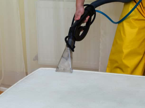 This is a photo of a man steam cleaning a dirty mattress works carried out by Tooting Carpet Cleaning