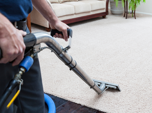 This is a photo of a man with a steam cleaner cleaning a cream carpet works carried out by Tooting Carpet Cleaning